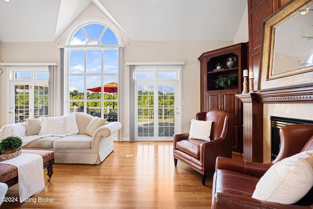 living room with vaulted ceiling, light wood finished floors, and a high end fireplace