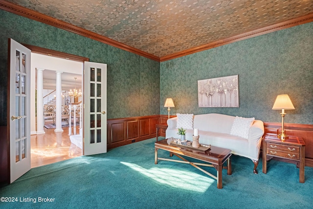 unfurnished living room featuring a wainscoted wall, decorative columns, ornamental molding, and french doors