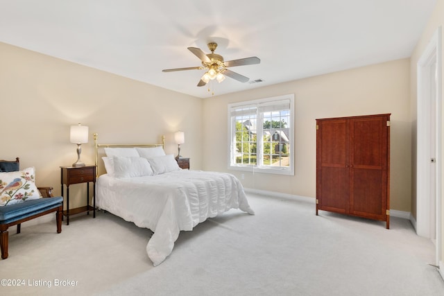 bedroom with light carpet, ceiling fan, visible vents, and baseboards