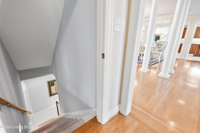 staircase with an inviting chandelier, decorative columns, baseboards, and wood finished floors