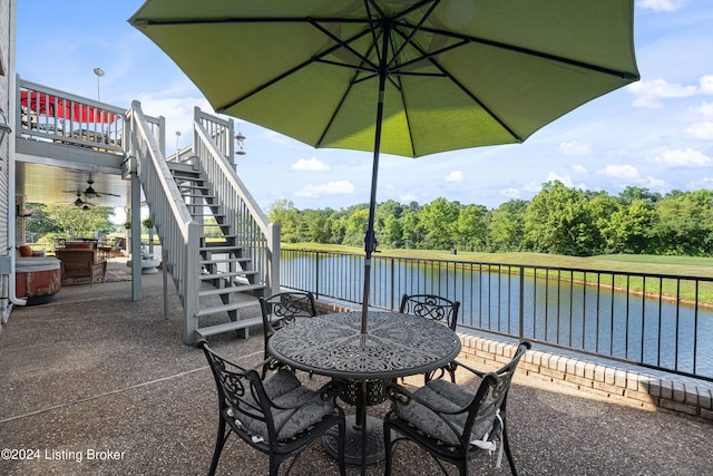 view of patio with stairway, outdoor dining area, and a deck with water view