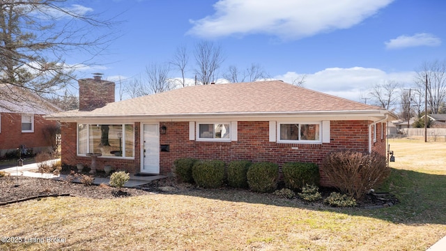 view of front facade with roof with shingles, brick siding, a chimney, and a front lawn