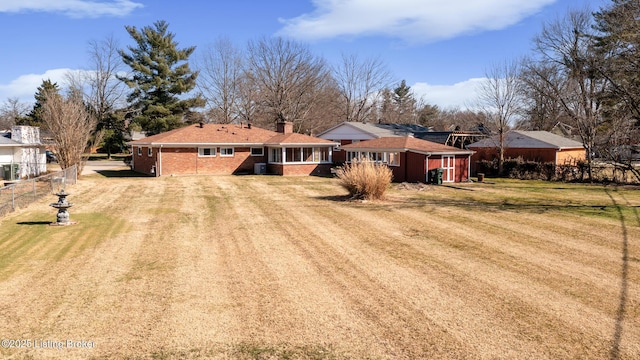 view of front of home with dirt driveway, a chimney, fence, a front yard, and brick siding