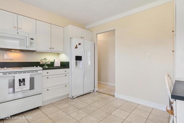 kitchen with light tile patterned floors, white appliances, white cabinetry, baseboards, and dark countertops