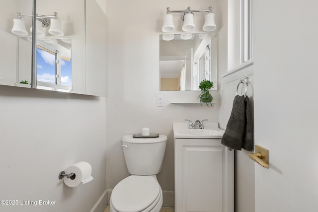 half bath with toilet, baseboards, and vanity