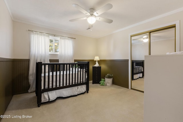 bedroom featuring carpet floors, a wainscoted wall, ornamental molding, and a closet