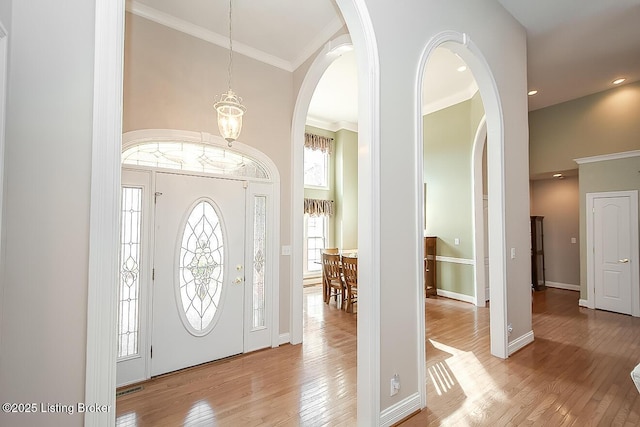 foyer with visible vents, baseboards, a towering ceiling, wood-type flooring, and ornamental molding