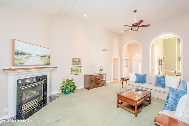 living room featuring baseboards, a ceiling fan, carpet floors, high vaulted ceiling, and a high end fireplace