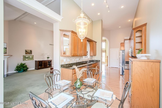 dining room with arched walkways, high vaulted ceiling, light carpet, baseboards, and beam ceiling