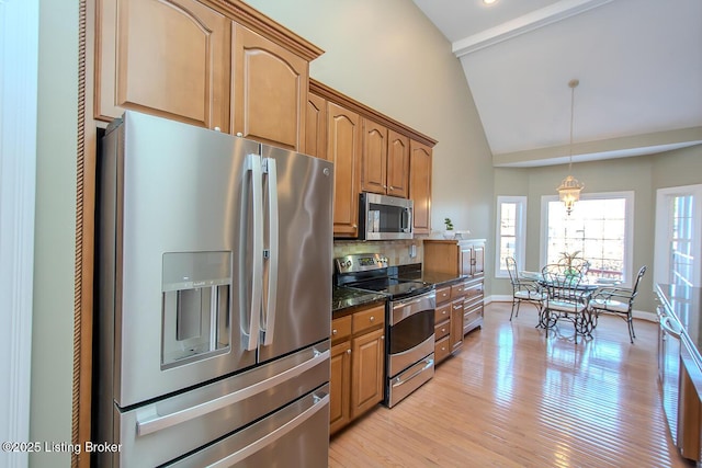 kitchen featuring stainless steel appliances, baseboards, light wood-style floors, dark stone countertops, and pendant lighting