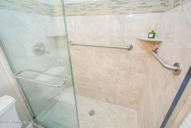 bathroom featuring toilet and a stall shower