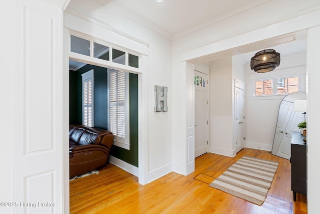 foyer with light wood-type flooring, baseboards, and crown molding