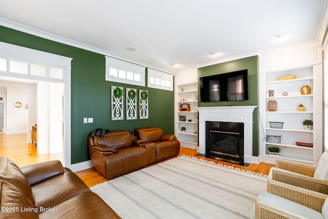 living room featuring a fireplace with flush hearth, wood finished floors, baseboards, built in features, and ornamental molding