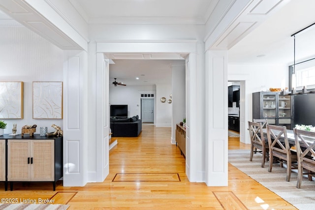 hall with light wood-style floors and ornamental molding