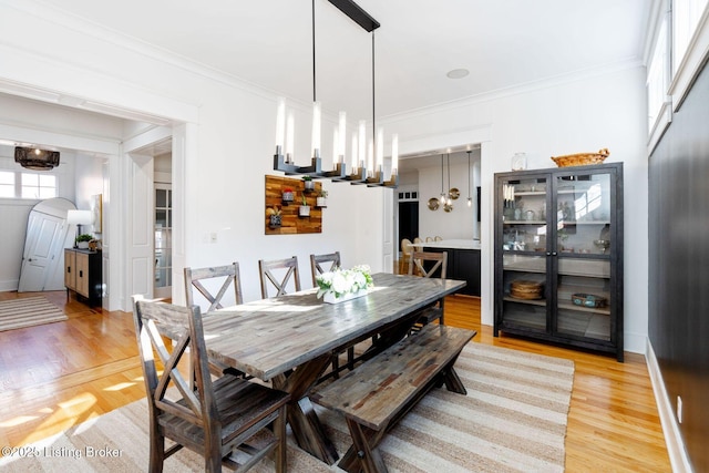 dining area with an inviting chandelier, light wood-style flooring, ornamental molding, and baseboards