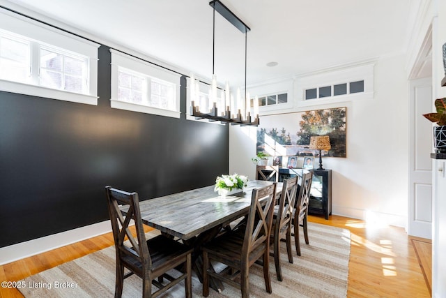 dining room featuring baseboards, light wood finished floors, and an inviting chandelier