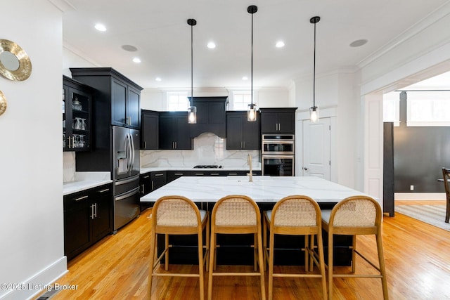 kitchen featuring dark cabinets, stainless steel appliances, a sink, and ornamental molding