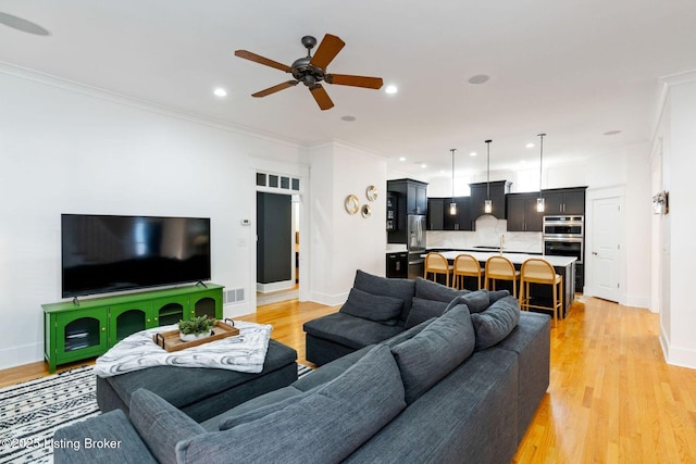 living room with visible vents, crown molding, and light wood-style flooring