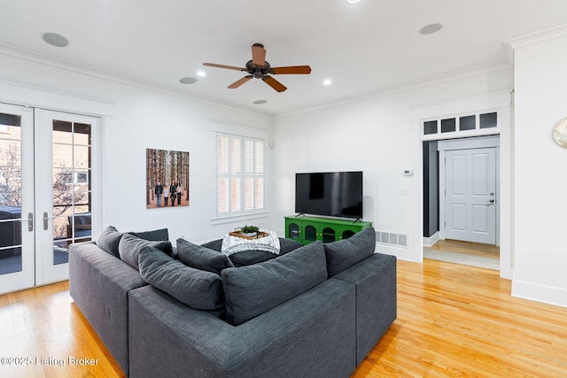 living area featuring ornamental molding, french doors, light wood-type flooring, and visible vents