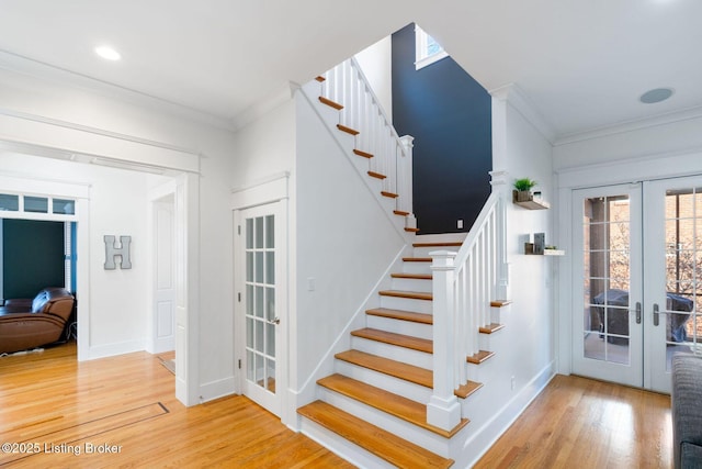 staircase with french doors, crown molding, baseboards, and wood finished floors