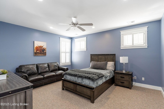 carpeted bedroom with baseboards, multiple windows, visible vents, and a ceiling fan