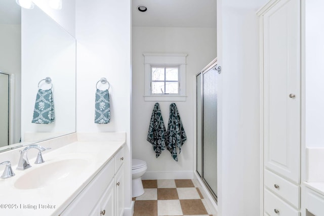 bathroom with baseboards, toilet, tile patterned floors, vanity, and a shower stall