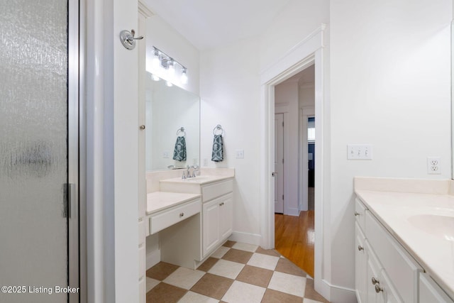 full bathroom with two vanities, a sink, baseboards, and tile patterned floors