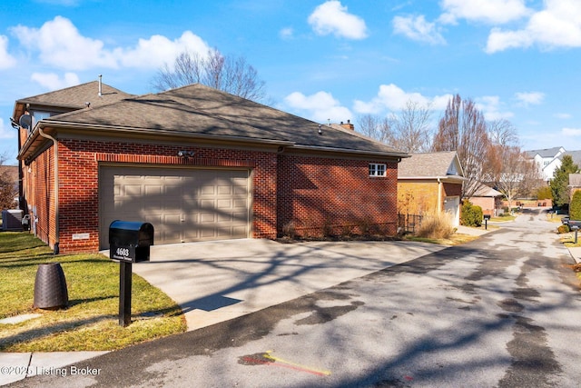 view of side of property featuring a shingled roof, concrete driveway, brick siding, and an attached garage