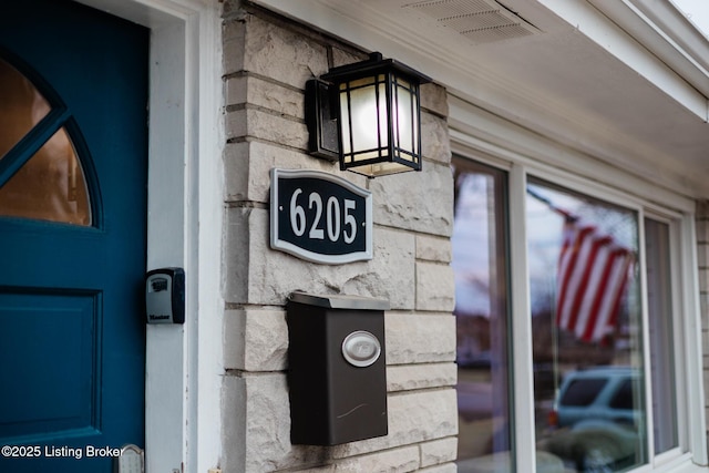 details featuring stone siding and visible vents