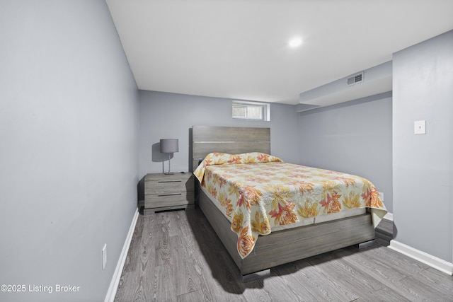 bedroom with wood finished floors, visible vents, and baseboards