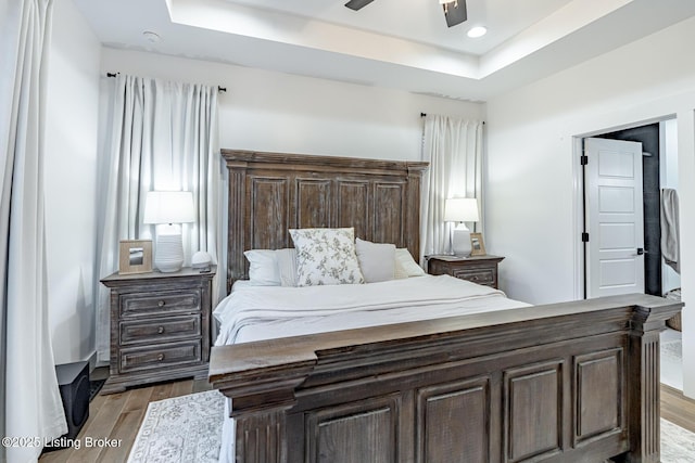 bedroom featuring light wood-style floors, recessed lighting, a raised ceiling, and a ceiling fan