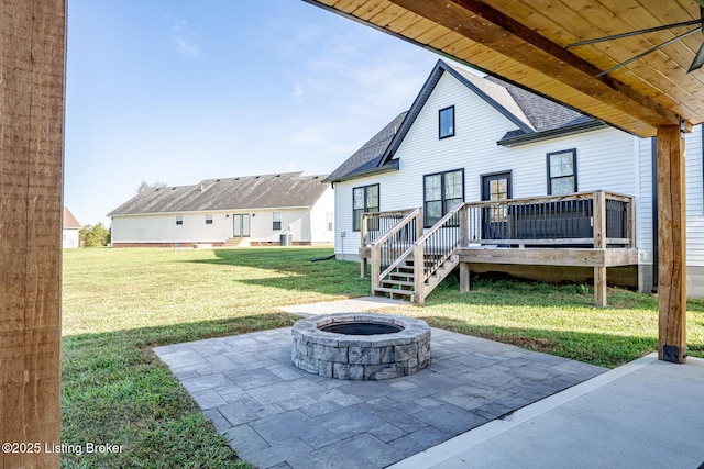 back of house with a shingled roof, a fire pit, a lawn, a deck, and a patio area