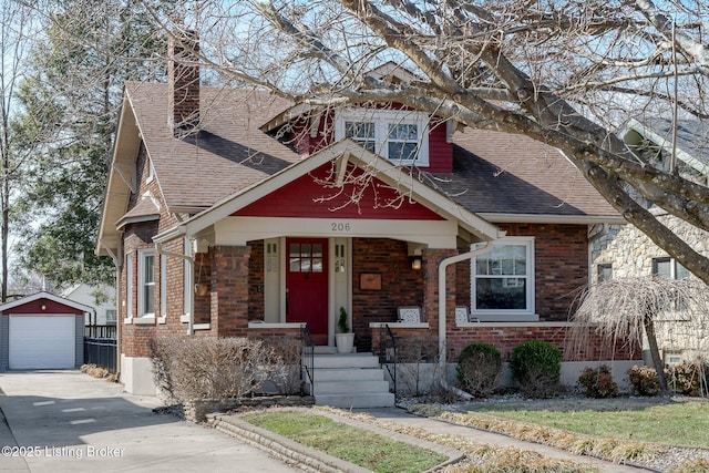 view of front of property featuring an outbuilding, concrete driveway, brick siding, and roof with shingles