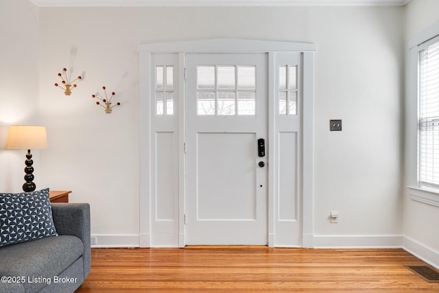 entrance foyer featuring baseboards, light wood-style flooring, visible vents, and a healthy amount of sunlight