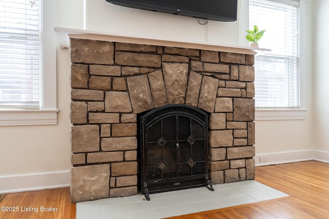 room details featuring baseboards, wood finished floors, and a stone fireplace