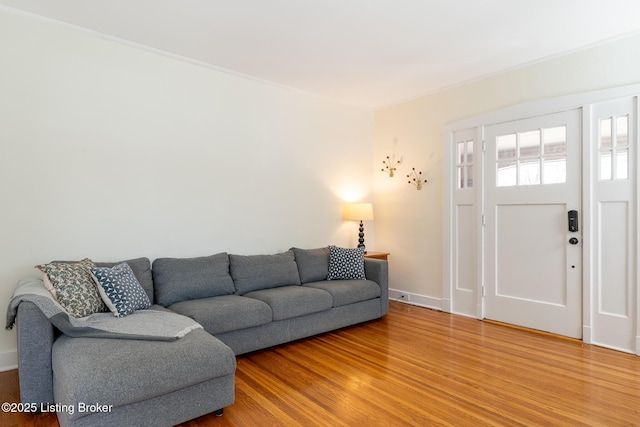 living room featuring light wood-type flooring, crown molding, and baseboards