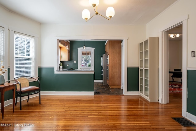 interior space featuring a notable chandelier, wood finished floors, visible vents, baseboards, and dark countertops