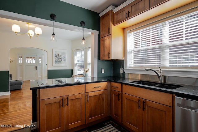 kitchen with arched walkways, dishwasher, decorative light fixtures, a peninsula, and a sink