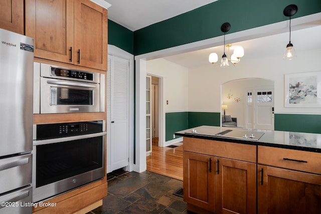 kitchen featuring dark countertops, stone finish floor, brown cabinets, and freestanding refrigerator