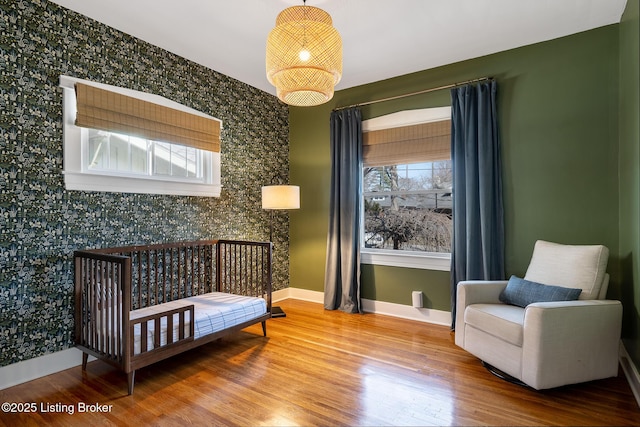 bedroom with multiple windows, baseboards, and wood finished floors