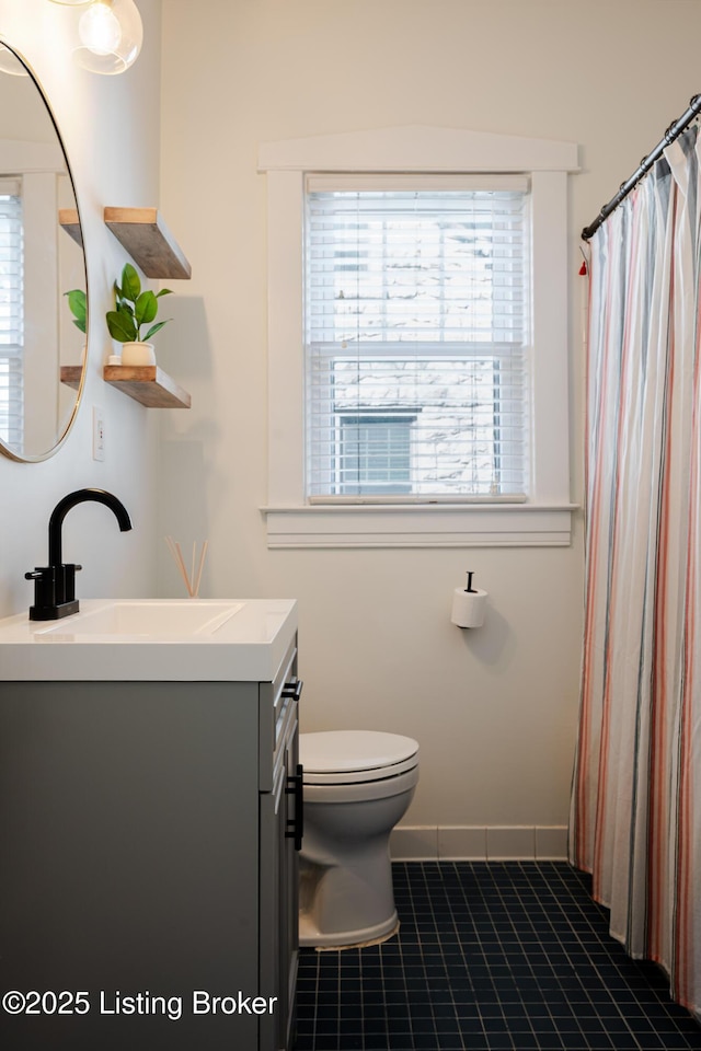 bathroom with tile patterned flooring, baseboards, vanity, and toilet