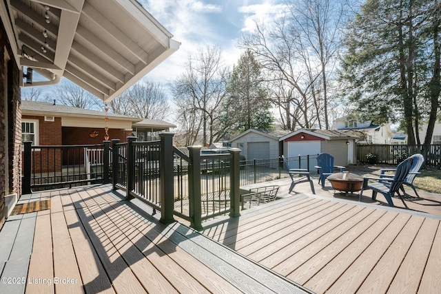 deck featuring an outdoor fire pit, fence, a patio, and an outdoor structure