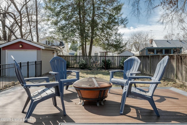 wooden deck featuring a detached garage, a storage unit, an outdoor fire pit, fence, and an outdoor structure