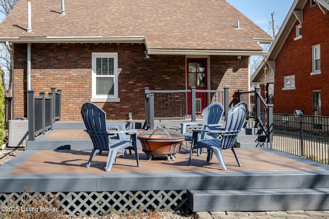 rear view of house with a shingled roof, a wooden deck, and brick siding