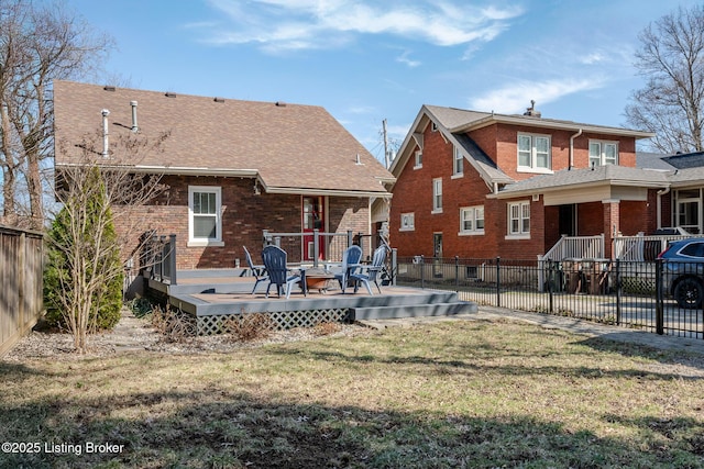 back of property featuring a yard, fence, and brick siding