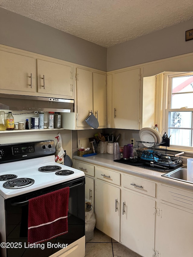 kitchen featuring a textured ceiling, light tile patterned floors, a sink, electric stove, and light countertops