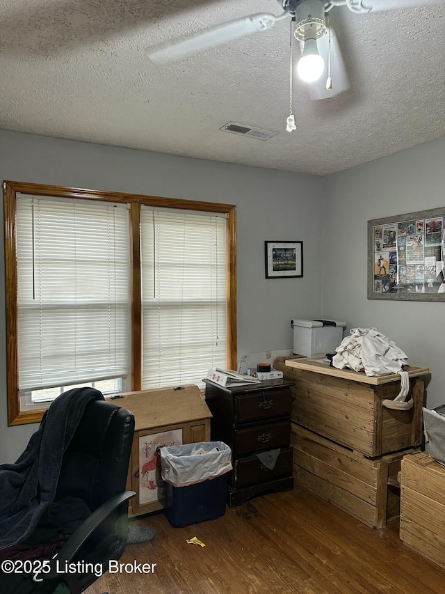 office area with dark wood-style floors, visible vents, and a textured ceiling