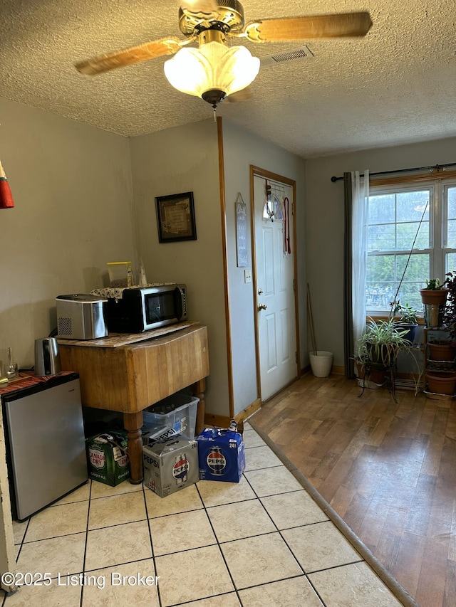 foyer with a textured ceiling, visible vents, and a ceiling fan