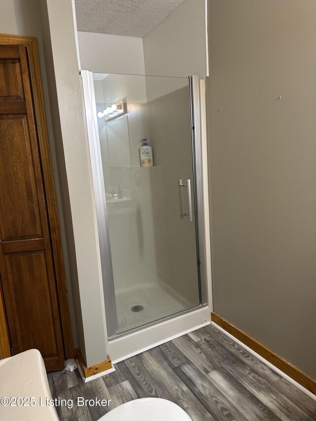 1683 Anneta Rd, Leitchfield, KY 42754 - bathroom with wood finished floors, a shower stall, baseboards, toilet, and a textured ceiling
