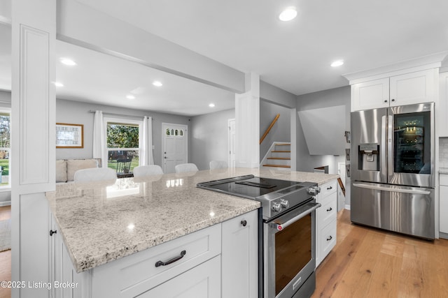 kitchen featuring light stone counters, light wood finished floors, stainless steel appliances, recessed lighting, and white cabinets